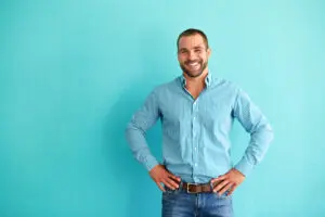 Smiling man standing in front of turquoise wall