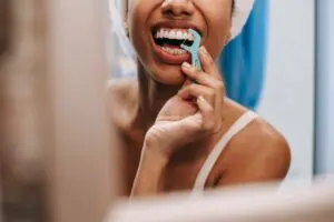  Photo by Sora Shimazaki: https://www.pexels.com/photo/reflection-of-woman-cleaning-teeth-5938299/ woman flossing teeth and showing gum line 