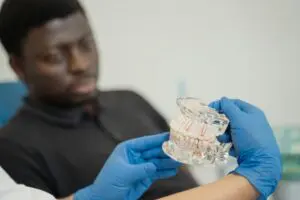 Photo by Tima Miroshnichenko: https://www.pexels.com/photo/a-dentist-holding-a-dental-cast-5355719/ Dentist informing their patient about the All-on-4 recovery process