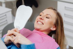 Photo by Photo By: Kaboompics.com: https://www.pexels.com/photo/smiling-woman-in-dentist-chair-looking-in-mirror-6627574/ woman smiling at her healthy smile reflection