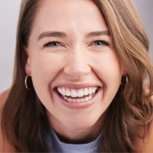 Studio portrait of a happy young woman posing against a grey background.