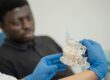 Photo by Tima Miroshnichenko: https://www.pexels.com/photo/a-dentist-holding-a-dental-cast-5355719/ Dentist informing their patient about the All-on-4 recovery process
